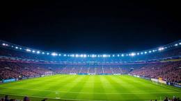 Italiensk fotbollsarena i kvällsmörker under blå strålkastare